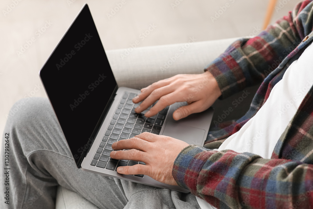Fototapeta premium Young man working with laptop in living room. Closeup