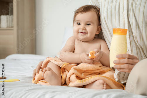 Baby sitting on bed in towe...