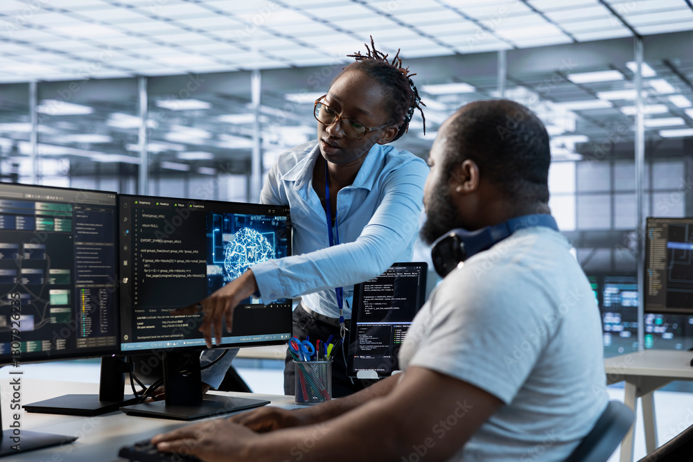 Manager showing engineer how to finish tasks in data center providing resources for different workloads. Team leader teaching IT specialist how to monitor supercomputers, pointing to screen Manager showing engineer how to finish tasks in data center providing resources for different workloads. Team leader teaching IT specialist how to monitor supercomputers, pointing to screen