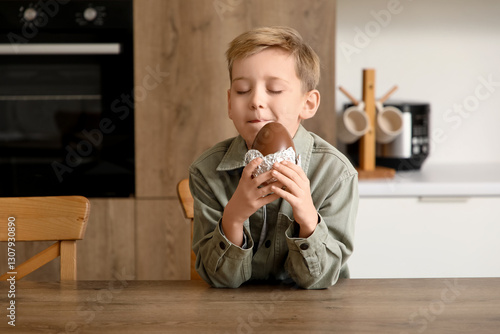 Canvas-taulu Little boy with chocolate egg in kitchen
