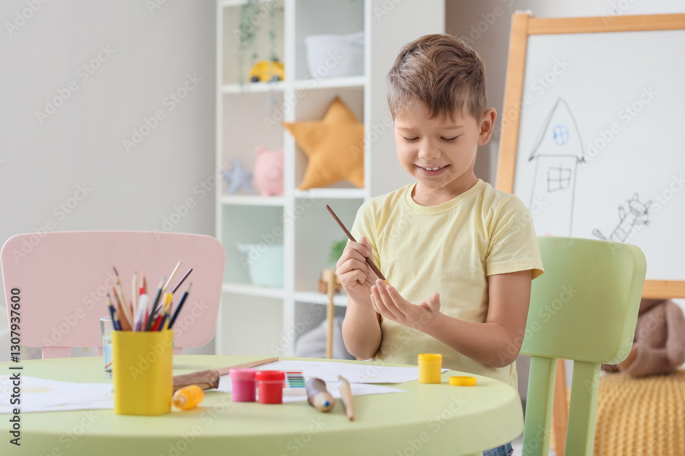 Little boy painting his hands at table in living room Little boy painting his hands at table in living room