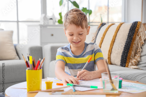 Smiling little boy with felt-tip pens drawing at home