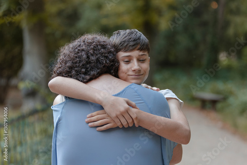 Hug from a happy teenage son to his mother. Tenderness, love, family.