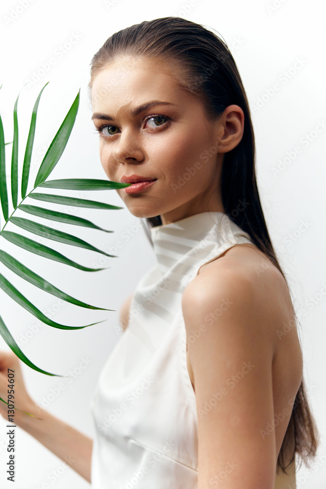Serene woman holding palm leaf in elegant white attire, showcasing natural beauty and grace, perfect for seasonal fashion and eco-friendly themes. Serene woman holding palm leaf in elegant white attire, showcasing natural beauty and grace, perfect for seasonal fashion and eco-friendly themes.
