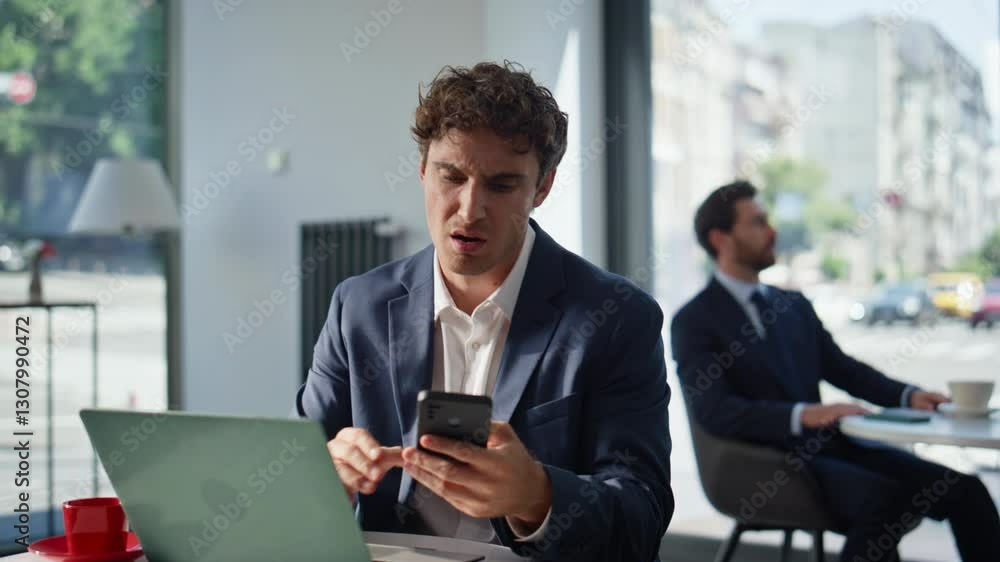 Nervous manager looking cellphone sitting at cafe table with laptop closeup Nervous manager looking cellphone sitting at cafe table with laptop closeup