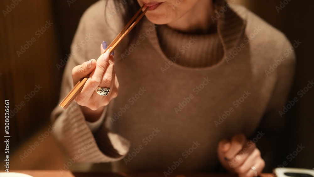 Obraz premium 女性が箸を持ち食事をする