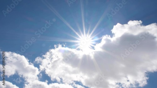 The sun peeking through the clouds in the blue sky