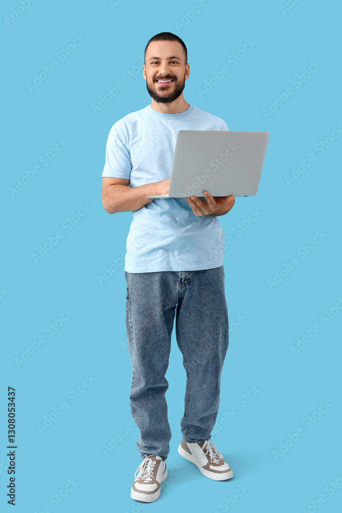 Smiling young man with laptop on blue background Smiling young man with laptop on blue background