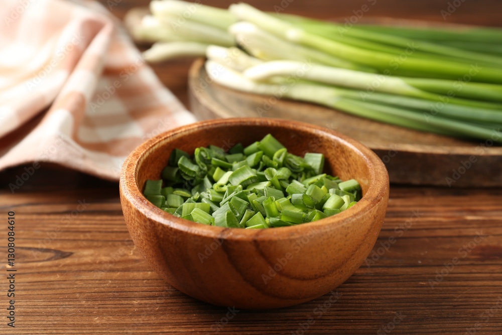 Cut fresh green onions in bowl on wooden table, closeup Cut fresh green onions in bowl on wooden table, closeup