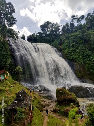 Beautiful waterfall cascading beside vibrant green rice terraces with a rustic hut. Perfect for travel, nature, agriculture, and eco-tourism projects.