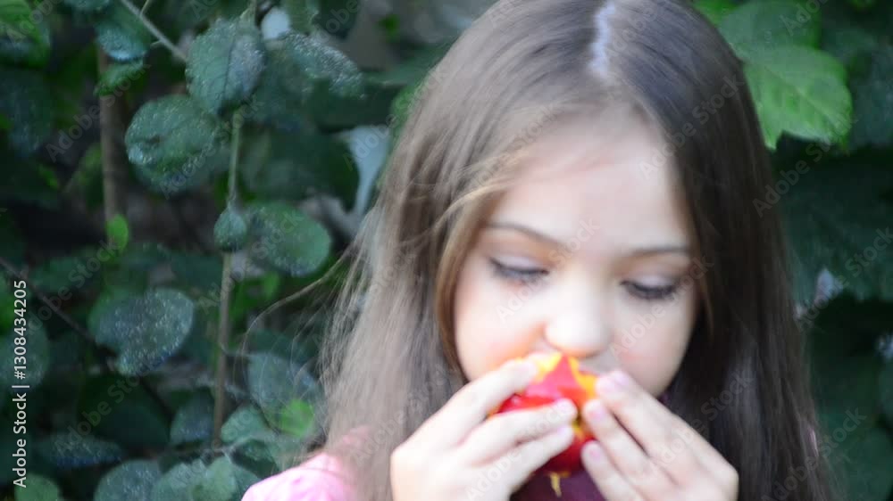Happy young girl with long hair eat tasty juicy yellow peach. Kid sit near the table. Nice fresh healthy food for breakfast or dinner. She handle fruit gently and carefully with two hands. Happy young girl with long hair eat tasty juicy yellow peach. Kid sit near the table. Nice fresh healthy food for breakfast or dinner. She handle fruit gently and carefully with two hands.