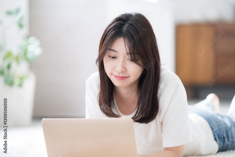 Woman searching on computer in prone position Image of studying online at home, etc. Woman searching on computer in prone position Image of studying online at home, etc.
