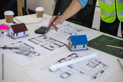 Wallpaper Mural A person is drawing a house on a table with a calculator and a ruler. The person is wearing a yellow vest
 Torontodigital.ca
