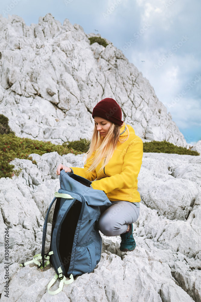 Naklejka premium Woman packing her backpack in mountains travel solo girl hiking in Greece active adventure lifestyle, female traveler exploring Rhodes island autumn season vacations outdoor trip