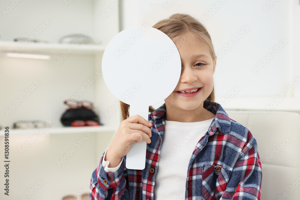 Little girl covering her eye at ophthalmologist office, space for text Little girl covering her eye at ophthalmologist office, space for text