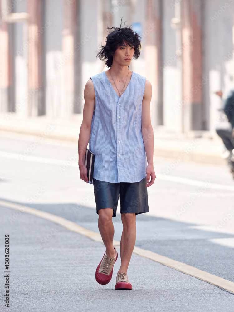 Portrait of handsome Chinese young man wearing undershirt and shorts posing in the street, young guy with black curly hair with urban background. male fashion, cool Asian young man lifestyle. Portrait of handsome Chinese young man wearing undershirt and shorts posing in the street, young guy with black curly hair with urban background. male fashion, cool Asian young man lifestyle.
