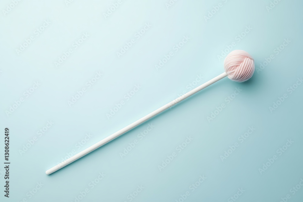 Pink yarn ball on a stick against a light blue background. Pink yarn ball on a stick against a light blue background.