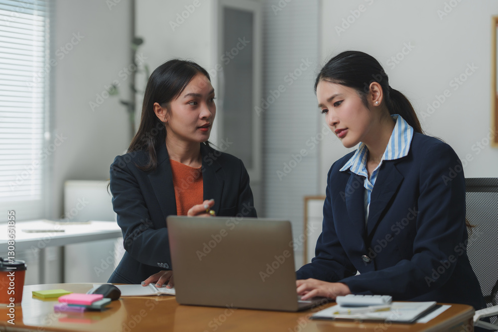 Businesswomen collaborating on laptop in office meeting Businesswomen collaborating on laptop in office meeting