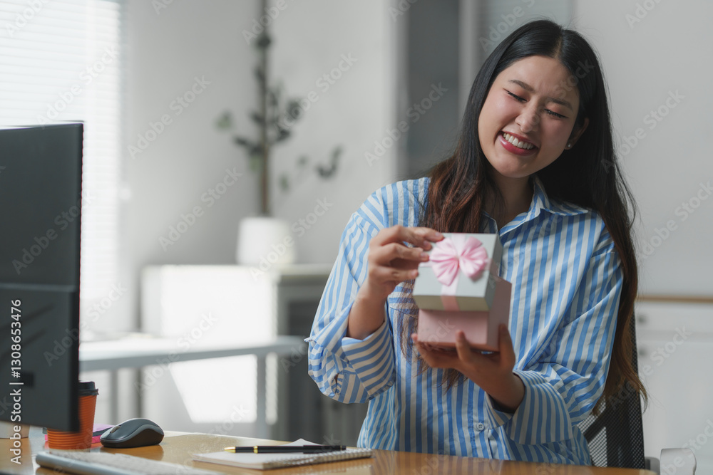 Happy businesswoman opening gift box at office desk