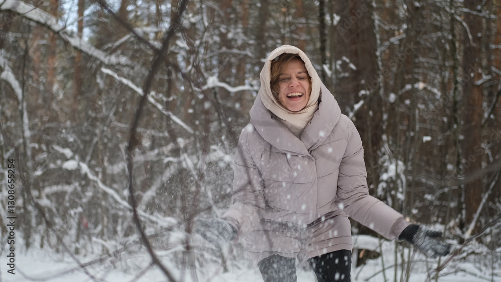 Naklejka premium Young pretty woman in warm winter clothes walking in snowy park