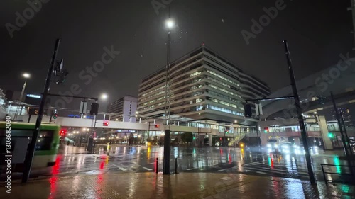 A rainy night in Tokyo, illuminated streets with traffic and tall buildings in the background