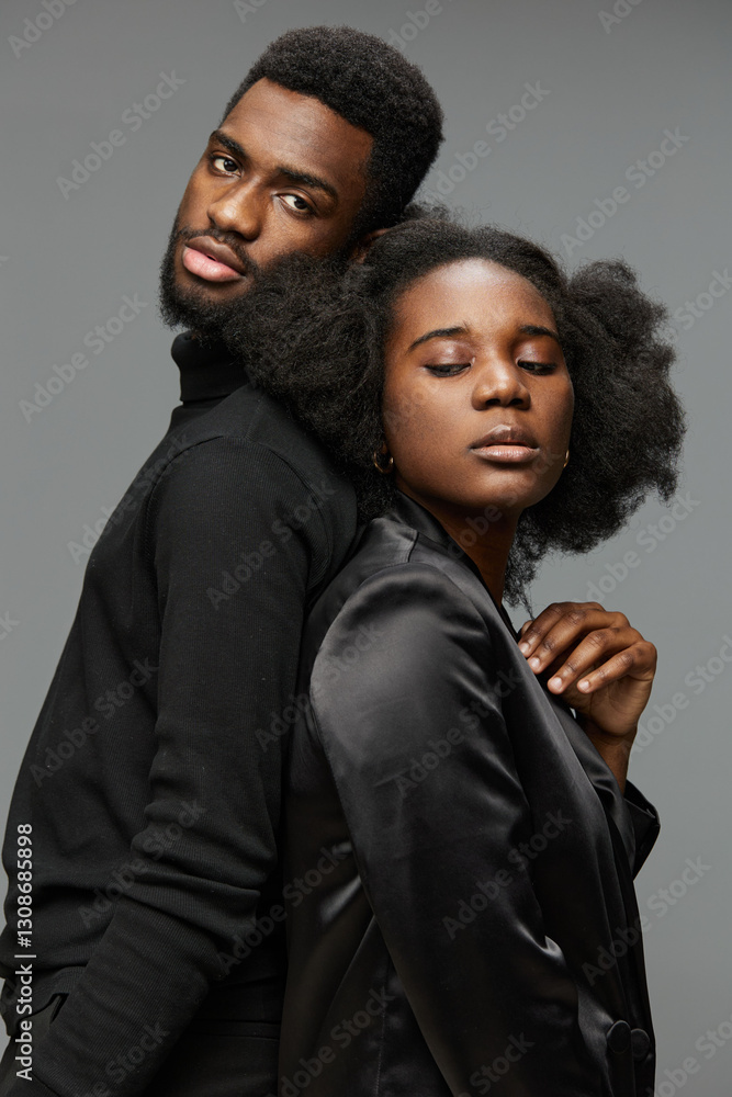 Fototapeta premium Elegant portrait of a Black couple with stylish attire, showcasing intimacy and sophistication against a grey background, perfect for romantic or fashion themed projects