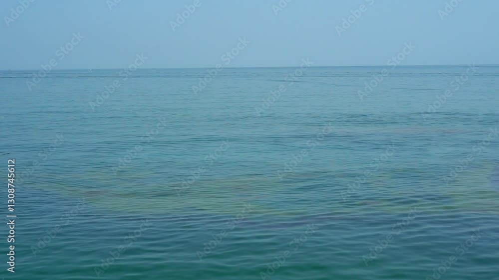 Oil slick on the calm ocean surface with barely visible rainbow reflection under a clear sky. Concept of ecology and technological pollution of the environment. Cell phone video footage Oil slick on the calm ocean surface with barely visible rainbow reflection under a clear sky. Concept of ecology and technological pollution of the environment. Cell phone video footage