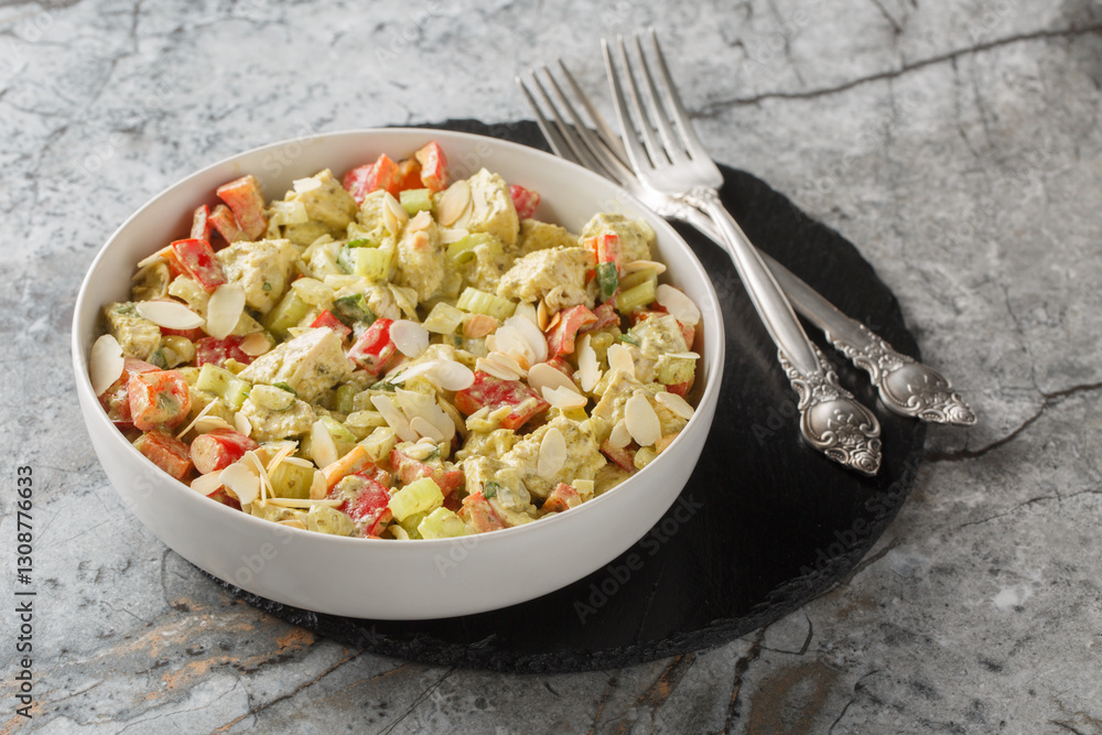 Healthy pesto salad with boiled chicken breast, fresh vegetables and almonds close-up in a plate on the table. Horizontal