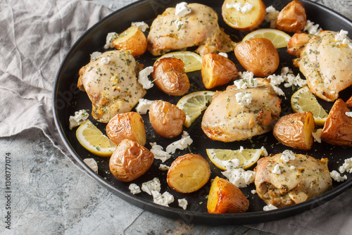 Greek cuisine Skinless chicken thighs with feta, lemon, garlic and potatoes close-up in a frying pan on the table. Horizontal