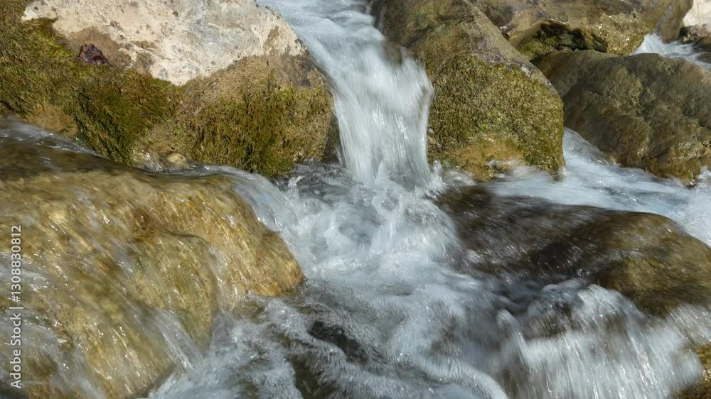 Clear water flows over mossy rocks in slow motion showcasing natural textures Clear water flows over mossy rocks in slow motion showcasing natural textures