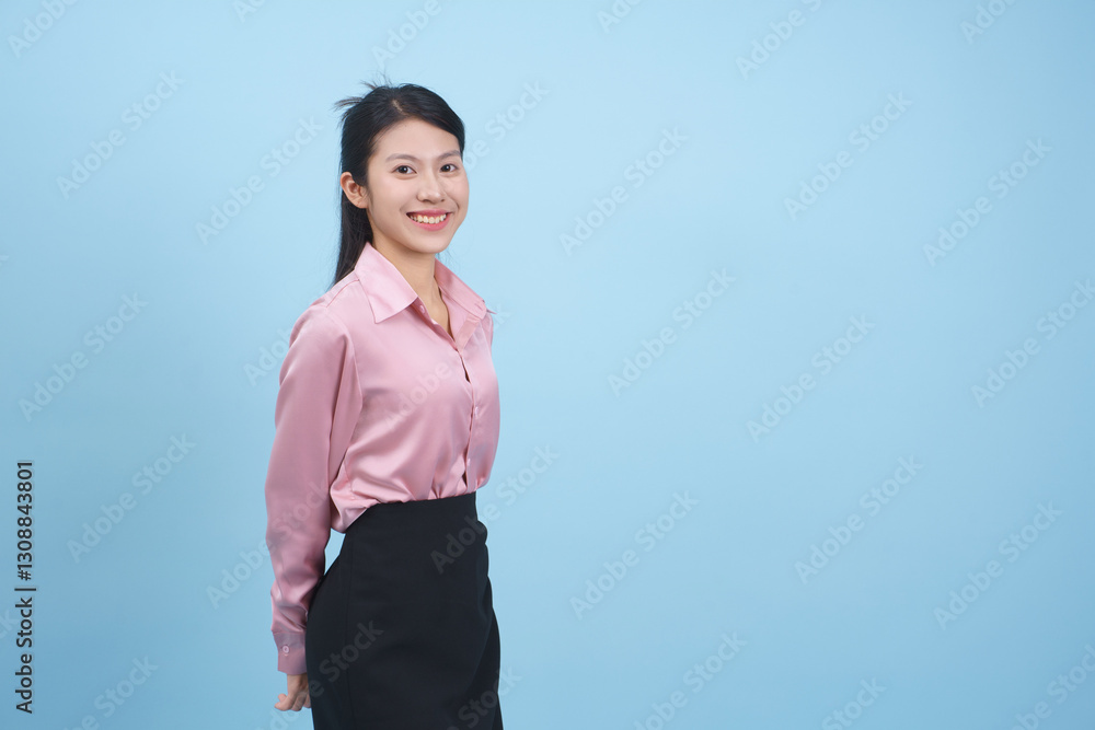 Young Asian woman smiles while posing against a light blue background during a professional photo session in a studio Young Asian woman smiles while posing against a light blue background during a professional photo session in a studio