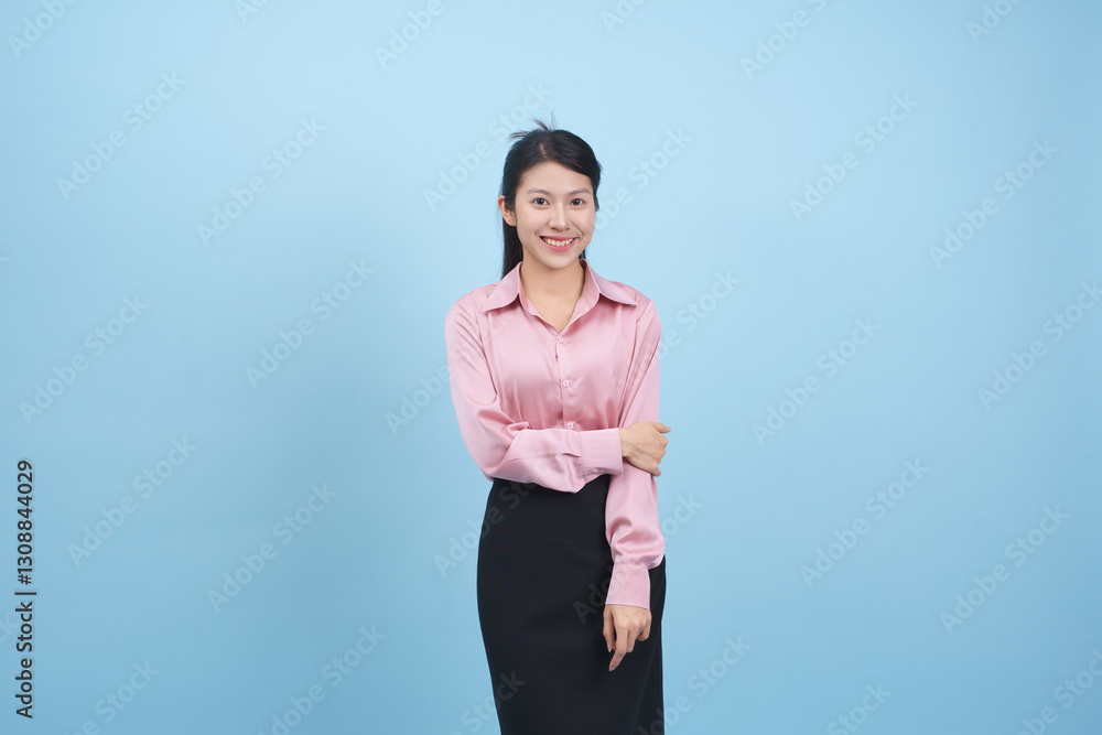 Young woman wearing a pink blouse and black skirt poses cheerfully against a light blue background in a bright indoor setting Young woman wearing a pink blouse and black skirt poses cheerfully against a light blue background in a bright indoor setting