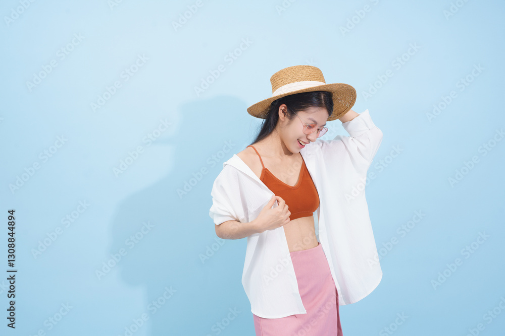 Woman in modern summer fashion poses against a light blue background, showcasing a stylish look and confidence Woman in modern summer fashion poses against a light blue background, showcasing a stylish look and confidence