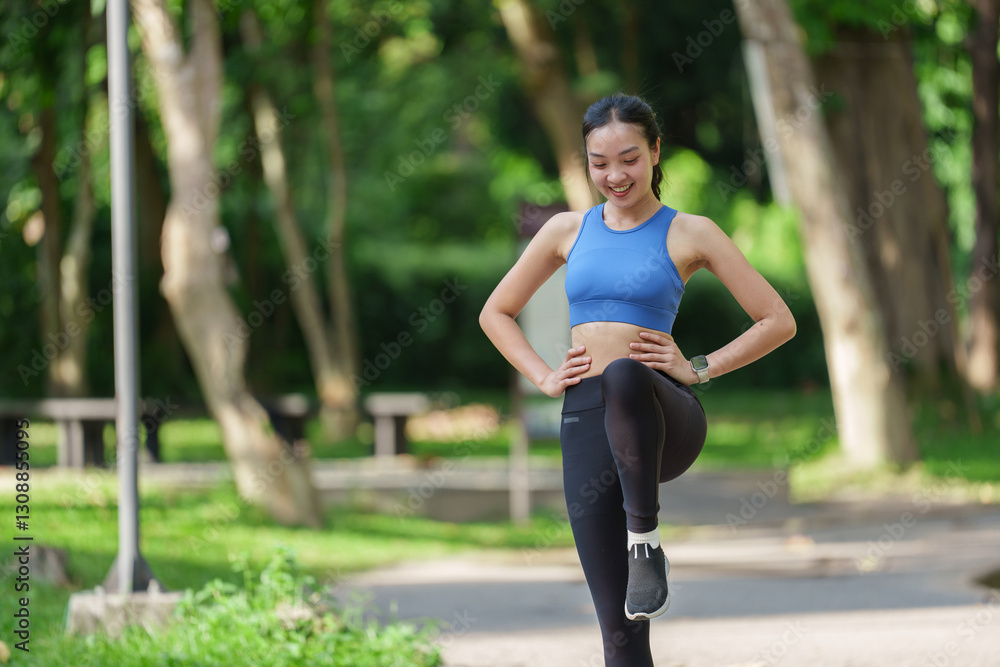 Happy fitness woman warming up her legs before running, enjoying a refreshing morning workout in a vibrant green park filled with trees and benches in the background Happy fitness woman warming up her legs before running, enjoying a refreshing morning workout in a vibrant green park filled with trees and benches in the background