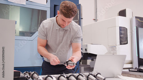 Tableau sur toile Male Engineer Measuring Components Whilst Looking At Laptop