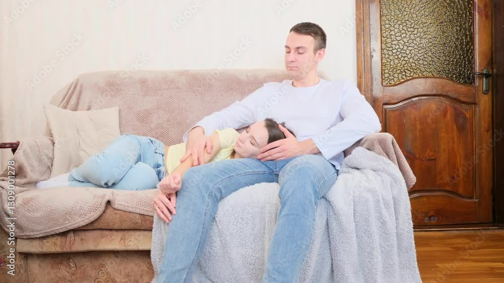 Young couple relax on cozy sofa, hugging, enjoy weekend in living room at home