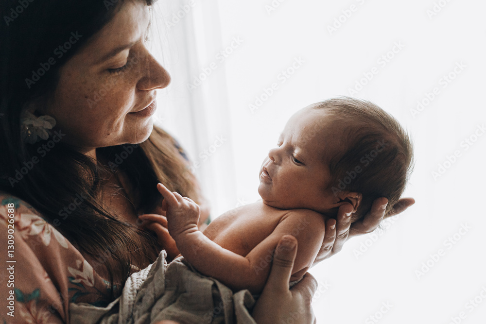 Happy Mother holding cute little baby in window light, close up. Happy Mothers day! Motherhood and parenthood. Adoption and fertility concept Happy Mother holding cute little baby in window light, close up. Happy Mothers day! Motherhood and parenthood. Adoption and fertility concept