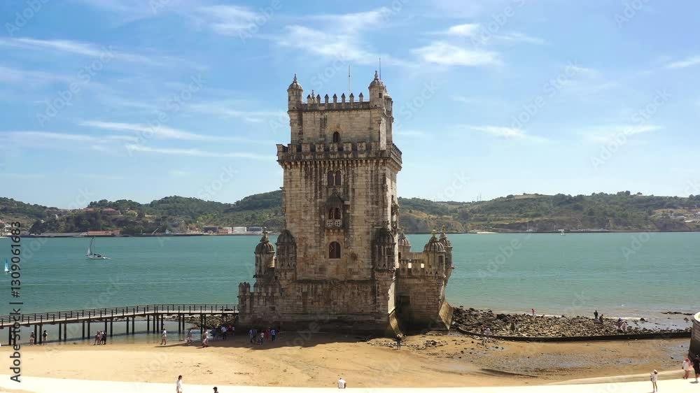 Aerial drone shot of Belem Tower, a historic fortress on the Tagus River in Lisbon, with tourists visiting and exploring the iconic monument Aerial drone shot of Belem Tower, a historic fortress on the Tagus River in Lisbon, with tourists visiting and exploring the iconic monument