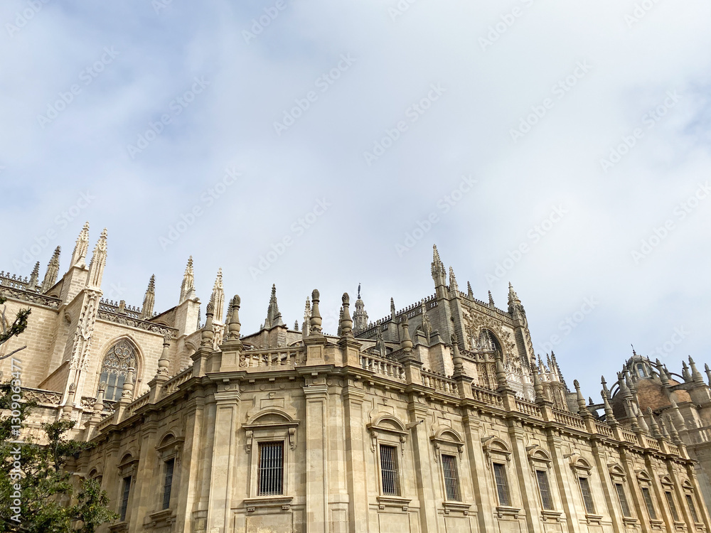 Gothic cathedral facade with intricate stone details, pointed arches, and ornamental windows against a cloudy sky. Gothic cathedral facade with intricate stone details, pointed arches, and ornamental windows against a cloudy sky.