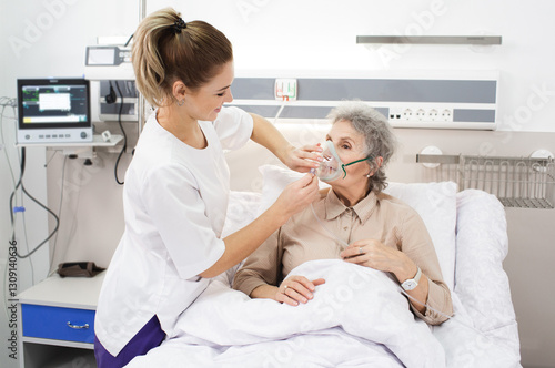 A nurse provides care to an elderly woman using a breathing mask in a medical clinic environment