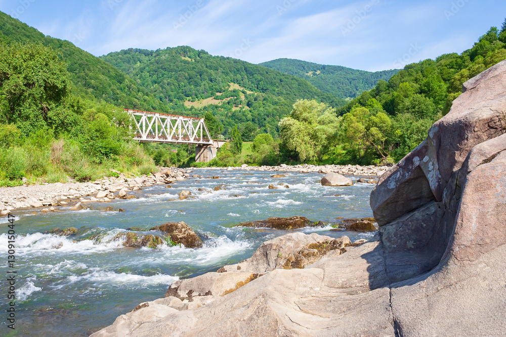 river flows through the valley in carpathian mountains. scenic view. shallow water reveals stones. beautiful landscape in summer on an sunny morning. blue sky with cloud
