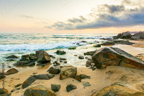Obraz na płótnie summer vacation landscape at the beach. dramatic seascape at sunrise. calm wave washing the coast with sand and rocks. beautiful view of sky with sun and cloud above horizon w salonie