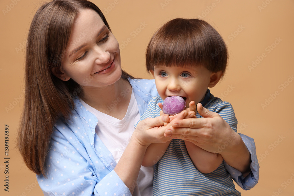 Mother and baby eating tasty mochi on brown background Mother and baby eating tasty mochi on brown background