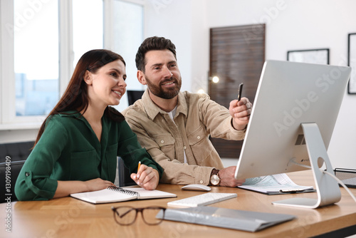 Colleagues working with computer at desk in office