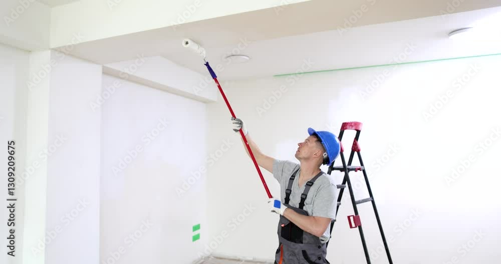 An experienced and skilled painter is expertly using a roller to paint the ceiling in a newly renovated room