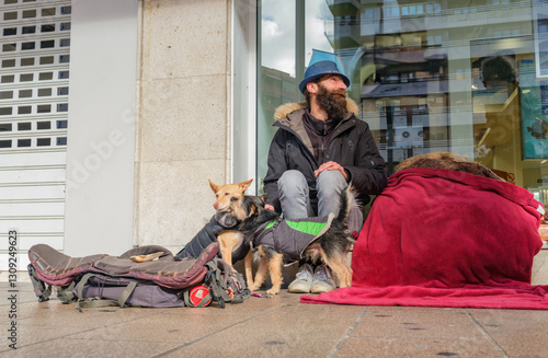 Homeless man sitting on sidewalk with his two dogs