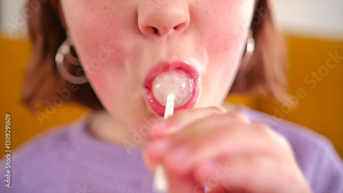 Child enjoying a lollipop in a vibrant indoor setting