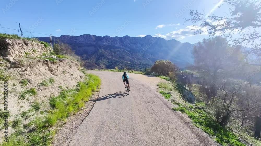 Epic shot of a cyclist riding a road bike along a scenic coastal highway.The sun casts long shadows as the cyclist enjoys a solo ride on a beautiful day.Perfect for travel, sports,and active lifestyle Epic shot of a cyclist riding a road bike along a scenic coastal highway.The sun casts long shadows as the cyclist enjoys a solo ride on a beautiful day.Perfect for travel, sports,and active lifestyle