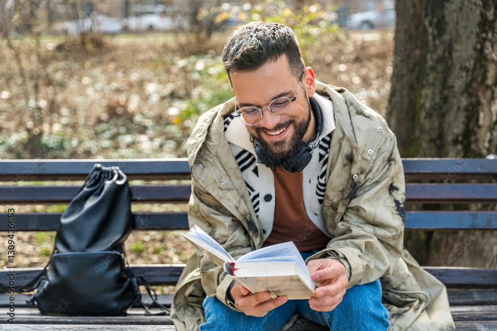 Young curious religious man, reading a book about religion, while sitting in the park on bench. Finding God male, happy and hungry for knowledge about faith. Christian or muslim read Bible or Quran. Young curious religious man, reading a book about religion, while sitting in the park on bench. Finding God male, happy and hungry for knowledge about faith. Christian or muslim read Bible or Quran.