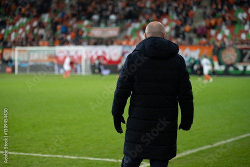 Obraz na płótnie Head coach's back and soccer match at the stadium in the background. w salonie
